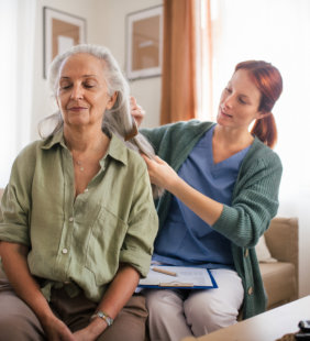 female caregiver combing the hair of elderly woman