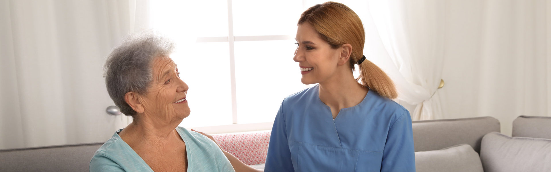 female caregiver and elderly woman smiling