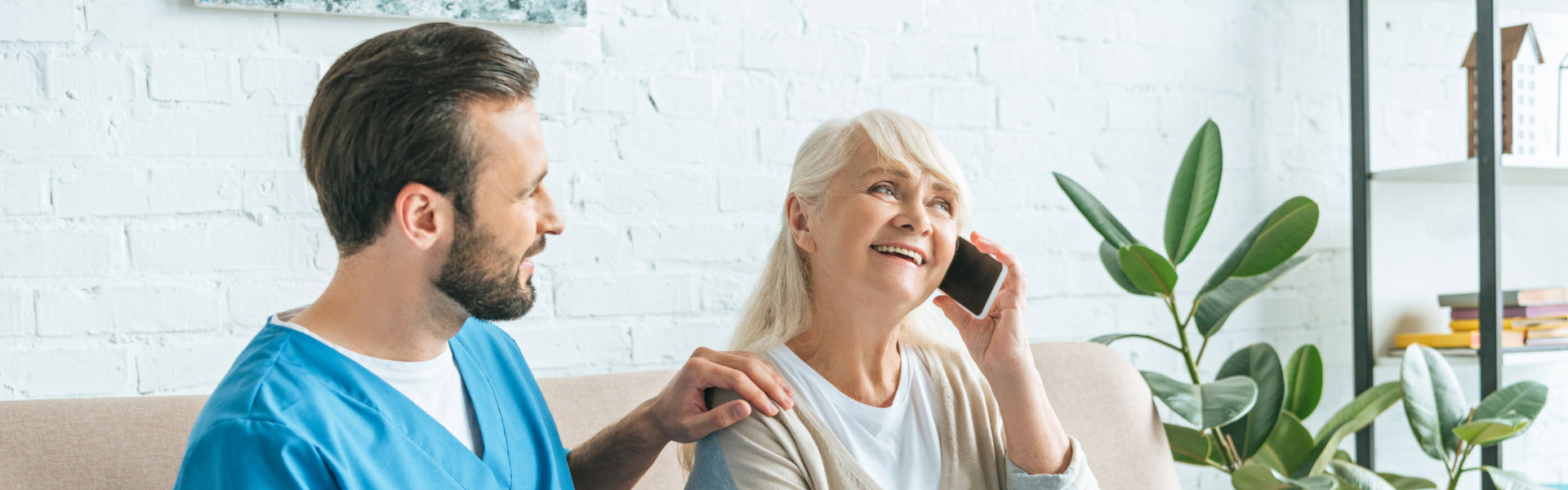 elderly woman calling on the phone with male caregiver